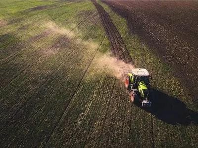 Tractor riding through a field leaving tracks.
